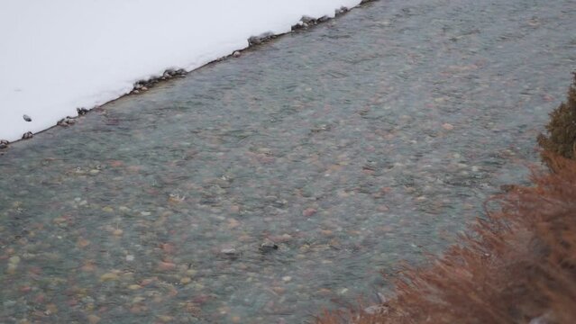 Landscape shot of river Bhaga flowing besides the snow covered river bed during the winter season at Jispa in Himachal Pradesh, India. River flows in the mountains during the winter season after snow.