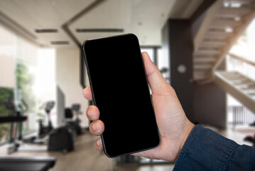 Hand held black phone With a blank white screen in the Gym in the morning light.