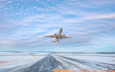 Fototapeta na wymiar Passenger airplane fly up over take-off runway amazing white clouds in the background - Snow-covered airport