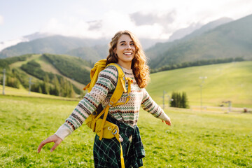 Young Woman walking on through green grass valley on background big mountains. Tourist traveler on...