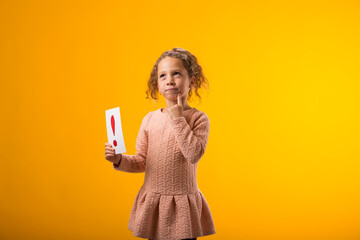 Thoughtful kid girl holding exclamation point card. Children, idea and knowledge concept