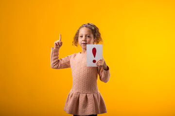 Surprised kid girl holding exclamation point card and holding finger up. Children, idea and...