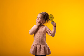 Thoughtful child girl holding paper bulb and pointing finger up. Success, motivation, winner, genius, idea concept