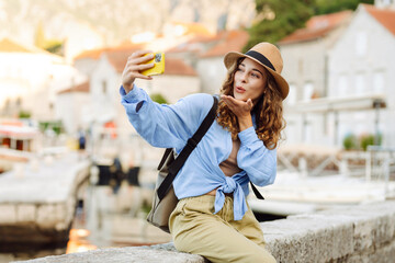 Young tourist walks the streets and takes selfie using smartphone camera. Lifestyle, travel,...