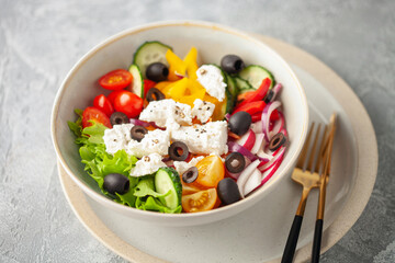 Greek salad of fresh cucumber, tomato, sweet paprika, lettuce, red onion, feta cheese and olives with olive oil. Healthy food.