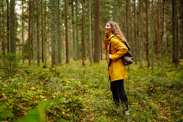 Pretty woman carrying a backpack in the forest  in the autumn season. Traveler enjoying nature. Concept of trekking, active lifestyle. Adventures.