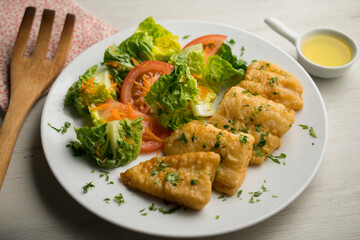Battered white fish served with a tomato salad.
