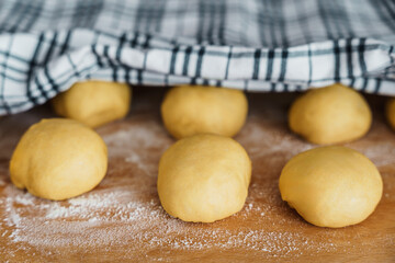 Rohe Teigkugeln auf einem Holzbrett. Germteig, Krapfen backen.