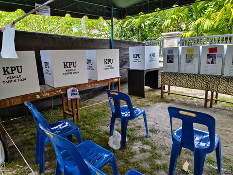 several ballot boxes on tables and benches, under signs
