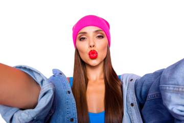 Charming blogger girl in a pink hat and blue body make selfie and sends air kiss isolated on vivid pink background