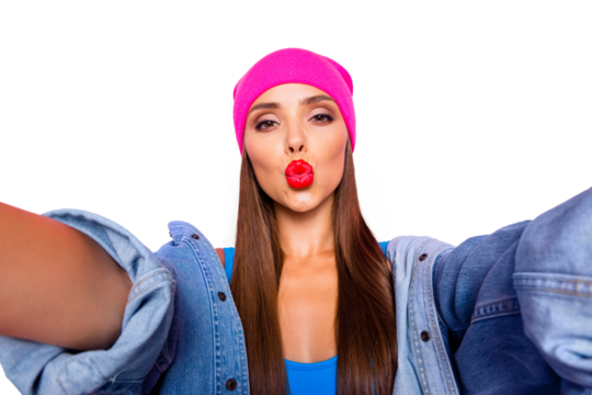 Charming blogger girl in a pink hat and blue body make selfie and sends air kiss isolated on vivid pink background