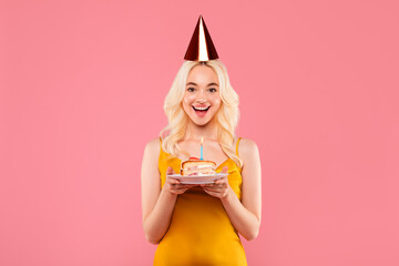 Excited blonde woman with birthday cake and candle, party mood