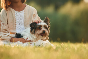 Dog in hands of cute little girl that is on the field