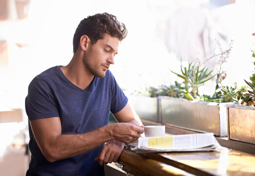 Man, coffee shop and relaxing with newspaper and cup, hot beverage and article for information. Male person, restaurant and reading paper for announcement, print and story for update and tea at cafe