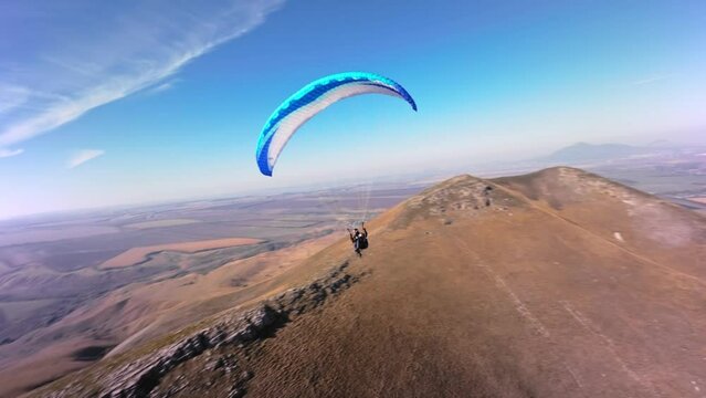 Filmed on a sports FPV quadcopter. A paragliding athlete flies on a sunny day next to a low mountain. Aerial view Adrenaline Concept, Drone Shot