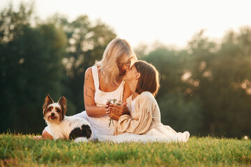 On the summer field. Mother with her daughter and cute dog