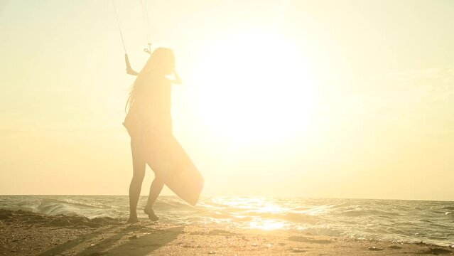 Summer sport with high waves and many dangers. Wind and wave speed. A man or woman stands on the beach and holds a sail with a board, extreme sport