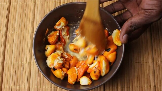 Crushing wild fruits of Trichilia emetica, also known as Natal mahogany or mafura, to make a creamy and delicious dessert