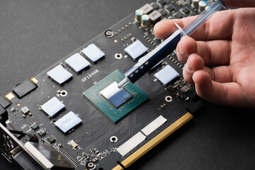 Applying thermal paste to a computer processor. Processor installation concept and cooling solution. Applying thermal paste during CPU installation close up in the motherboard.