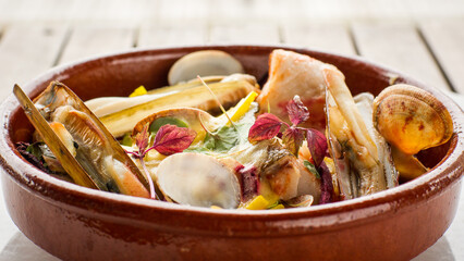 Close up of mixed shellfish and fish stew with chard, tomato and hollandaise sauce in bowl in...