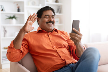 Cheerful mature indian man have video call with friend