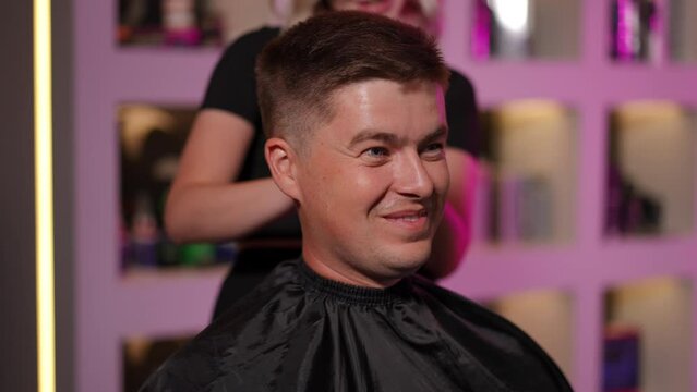 Close-up. Happy male client after a haircut, at a hairdressing course at the modern hairdressing academy. Slow motion