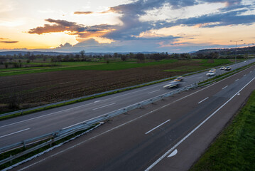 Cars drive at high speed on the highway through the rural landscape. Fast blurred highway driving. A scene of speeding on the highway.
