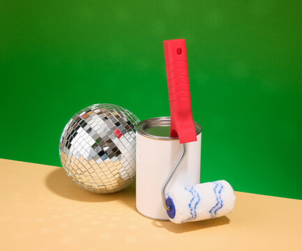 Paint roller and paint can, shiny mirror disco ball. Home renovation project.