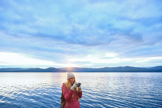 Woman with camera at the lake sunset
