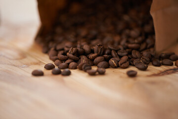 Table, closeup and fresh roasted coffee beans, spilling from a paper bag onto a vintage wood...