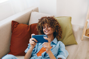 Just Chillin' on the Sofa: A Happy Woman Holding Her Phone at Home