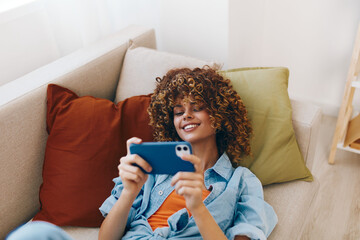 Just Chillin' on the Sofa: A Happy Woman Holding Her Phone at Home © SHOTPRIME STUDIO