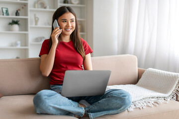 Naklejka premium Remote Business. Asian Woman Talking On Phone And Using Laptop At Home