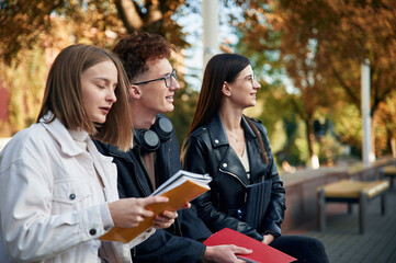 Sitting together. Three young students are outside the university outdoors