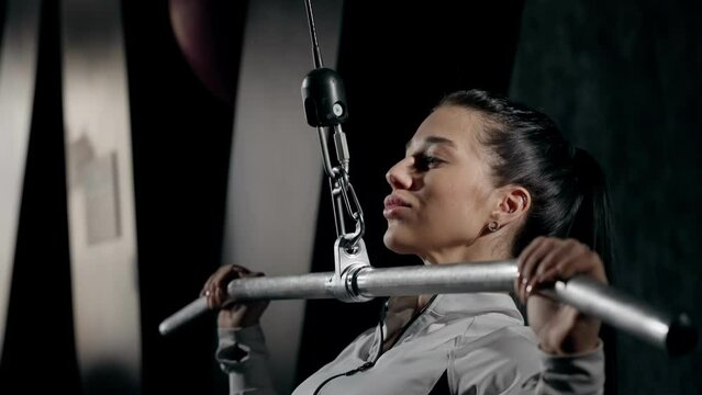 Focused Gym-Goer Performing Lat Pulldown Exercise. Woman engaged in lat pulldown routine at gym.