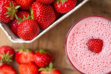 Close up of strawberry smoothie with strawberries on a wooden table