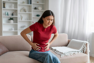 Stomach Ache. Sick Asian Woman Suffering From Acute Abdominal Pain At Home