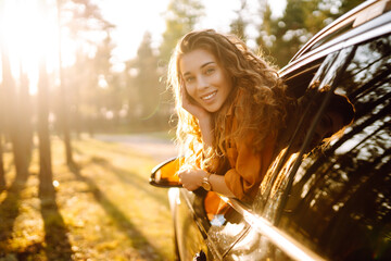 Happy woman leaning out of car window on summer road trip travel vacation.