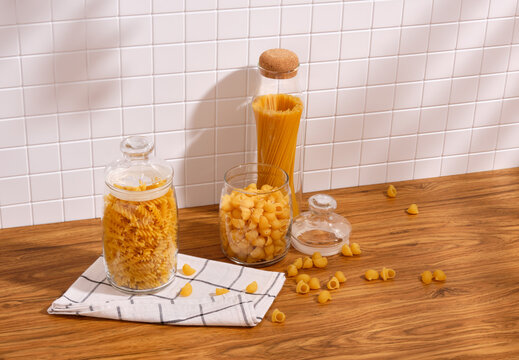 Different types of pasta in the kitchen. Some of the macaroni is scattered on the table. Copy space for text.