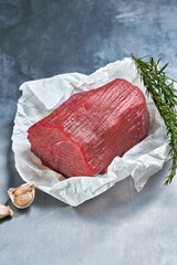 Fresh beef neck in parchment on a metal surface in a butcher shop.