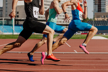 three male athletes sprinting on red track, muscles taut, competing fiercely