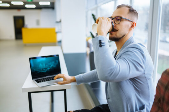 Young man wearing glasses working with laptop while sitting at his working place. Business, technology, study.