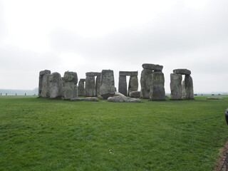 Naklejka premium Stonehenge on the green grass with grey sky