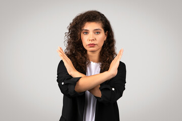 Assertive european businesswoman in suit making strong no gesture with her arms crossed in an X shape