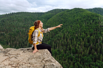 Naklejka premium Young woman with backpack on mountain peak enjoying nature. Hiking.Travel and tourism. Active lifestyle.