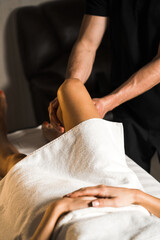 Obraz premium A professional masseur gives a massage to a young woman.Beautiful young woman enjoying massage in spa salon. Beauty treatment, skin care, wellbeing.Concept of massage and spa treatments