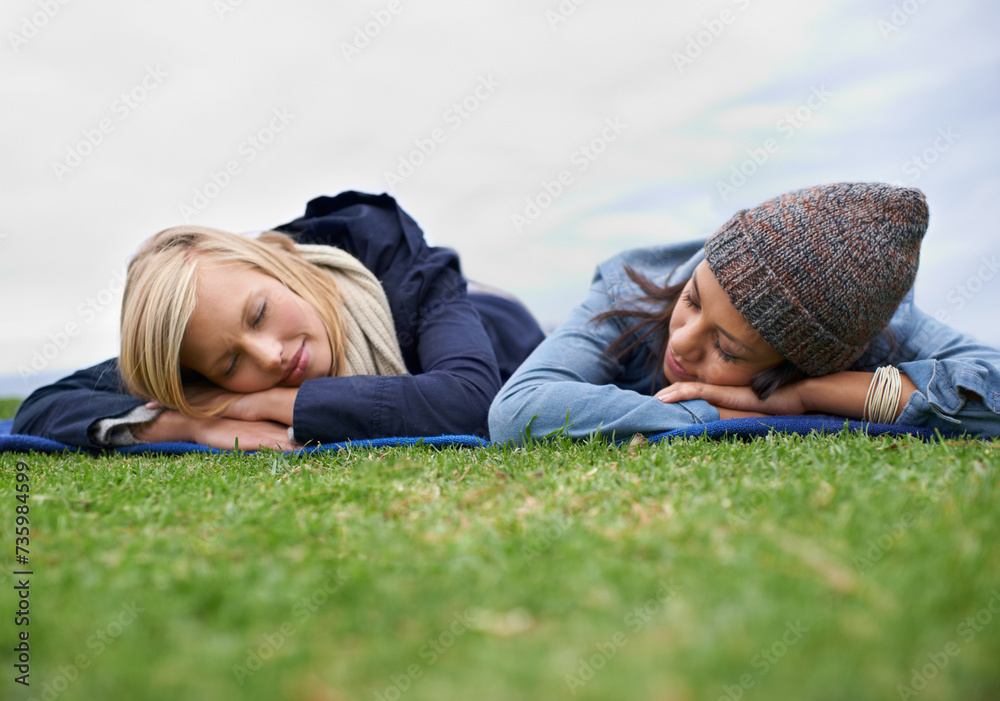 Poster Sleeping, grass and women relax in field with smile, happy and resting on weekend outdoors. Friends, countryside and people lying in meadow for bonding on holiday, vacation and adventure in nature