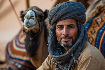 Foto op Canvas Berber with beard and turban, sitting in the desert in the company of his camels © Eomer2010
