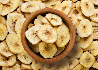 Dried bananas in a wooden plate, background. Top view
