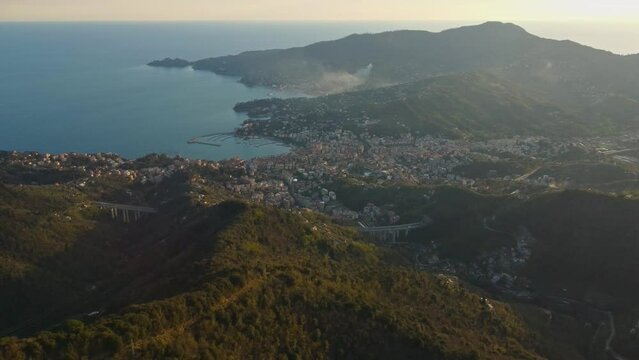 drone vista delle colline in Liguria. Sul fondo Rapallo. Mare e montagne al tramonto.

